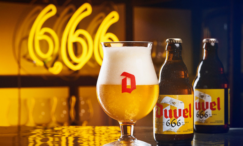 Duvel 666 glas en flesjes erachter op een bar met een 6,66 in een LED lamp erachter